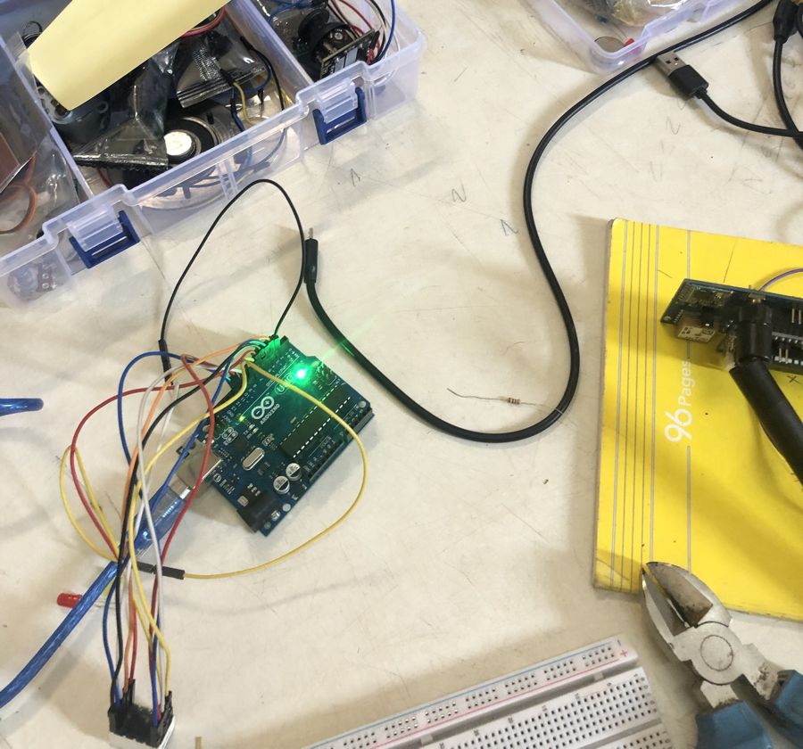 Carte Arduino Uno allumée et câblée sur l'établi, entourée de boîtes de composants